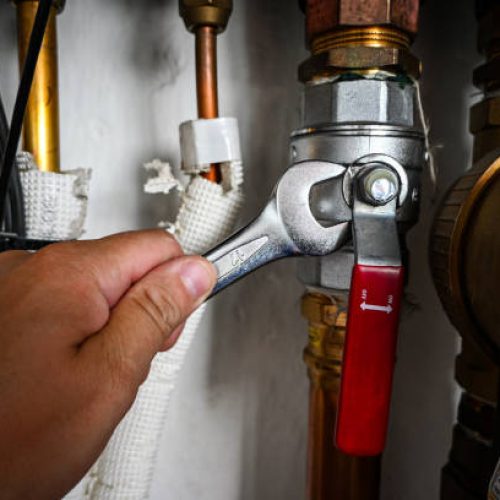 Plumber is tightening a nut on a water heater pipe using an adjustable wrench. Plumber is tightening a nut on a water heater pipe using an adjustable wrench.